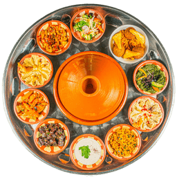 Geteilte Mezze-Tajine-Platte mit verschiedenen Vorspeisen und Tajine nach Wahl